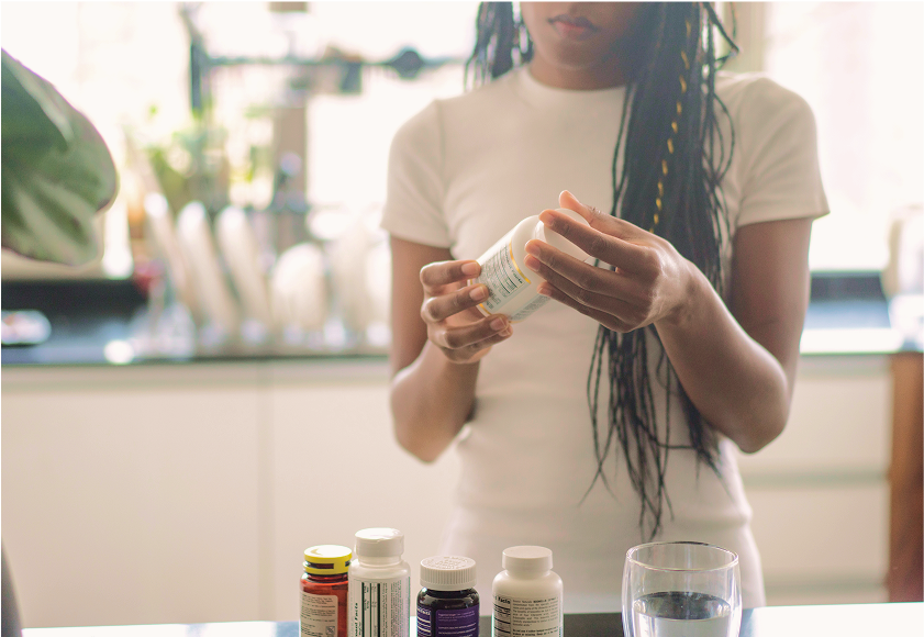 Woman reading a supplement bottle label in a bright kitchen
